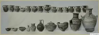 Two rows of pottery vessels from Marion, Tomb 79, with banded and circle decoration, set out on a white cloth