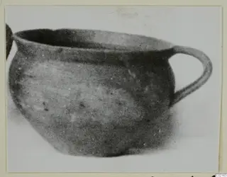 Round vessel with a wide open mouth and a single loop handle, photographed from the side