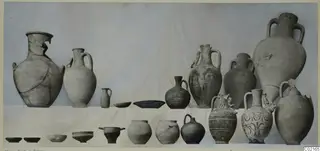 Pottery vessels from Marion, Tomb 37, arranged in two rows against a pale cloth backdrop.