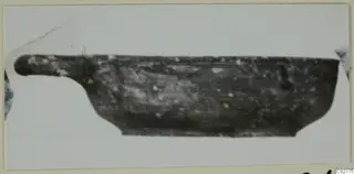 Side view of a dark, shallow Black Slip I-VI vessel with a long horizontal handle projecting to the left