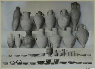 Pottery from Marion, Tomb 55: jars, jugs and bowls arranged in rows on a pale background.