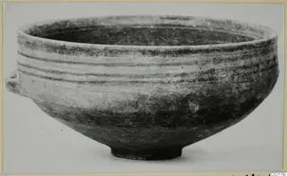 Black-on-Red pottery bowl with a small side lug, shown in side view against a plain background.