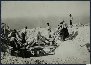 Men and a boy working at the central cistern at Vouni, with timber supports and ropes over the stone-lined pit.