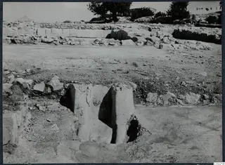 Excavation at the palace at Vouni, with upright stone blocks in the foreground and trees on the skyline.