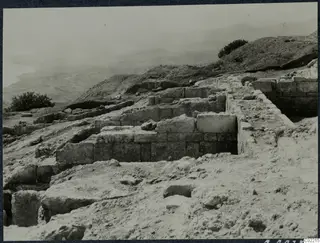 Excavated stone walls on a hillside at Vouni palace, with hills and the sea haze beyond