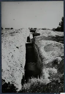 Narrow excavation trench at the palace at Vouni, with stones at its floor and bushes along its banks