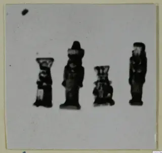 Four small dark figurines standing in a row on a pale card mount