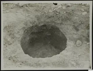 Excavation at Ayios Iakovos: a round pit in sandy soil with scattered stones around it