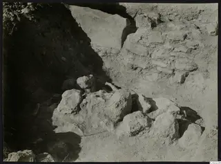 Excavation at Ayios Iakovos showing a cluster of large stones against a stone wall and earth bank
