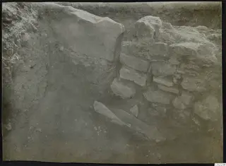 Excavated trench at Ayios Iakovos with a rubble stone wall and a long flat stone slab on the floor