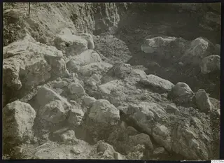 Excavation at Ayios Iakovos with many large pale stones and blocks lying in loose soil.