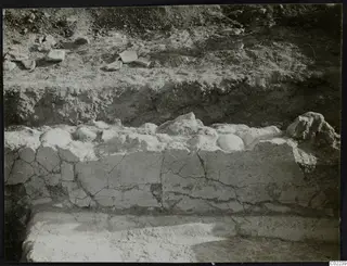Excavated site at Ayios Iakovos showing a low pale wall with rounded stones along its top
