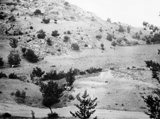 Excavation area at Ayios Iakovos seen from the west, with spoil heaps, a small group of people and rocky hills behind