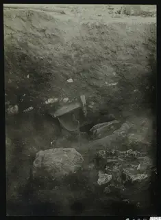 Excavation section at Kition with a curved water gutter set into the soil face and stone blocks below.