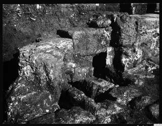Excavated stone walls and blocks at Kition, room 10, in a dug trench.