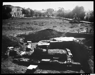 Excavated remains at Bamboula after the excavation, with a two-storey building with arches in the background.