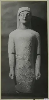 Limestone statue of a standing male figure, from Kition, photographed against a dark backdrop.