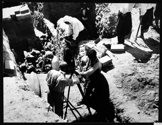 John Lindros filming at the excavation in Kition, with workers and excavated material around the trench