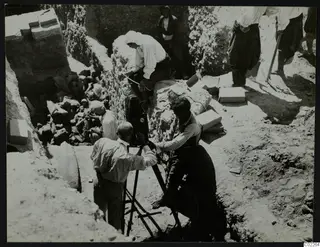John Lindros filming at the excavation in Kition, with workers and boxes of finds around the trench