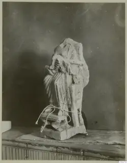 Limestone statue of a draped standing figure with its head and upper part broken away, on a square base
