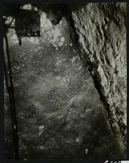 Excavation at Amathus: a cut earth or rock face on the right and a ground surface with small pale stones scattered across it