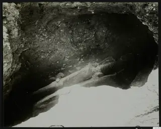 Skeleton lying extended in a rock-cut hollow at Amathus, with stones beside it.