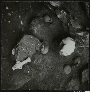 Tomb 11 at Amathus: finds in situ on the rock floor, with dark pots and a pale rounded fragment that may be bone.