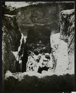 Amathus tomb during excavation, with a skeleton and pottery vessels lying on the floor of the chamber