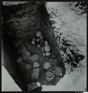 Finds in situ in Tomb 19 at Amathus: pottery vessels and stone slabs on the floor of a cut tomb pit.