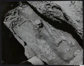 Excavation at Amathus showing a skeleton and scattered stones on a sloping rock-cut floor