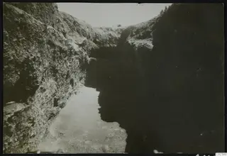 Excavation cutting at Amathus with steep stony walls and a sandy floor running away from the viewer.