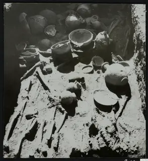 Skeleton and pottery vessels on the floor of a tomb during excavation at Amathus
