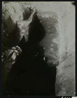 Deep excavation cutting at Amathus with pale objects on the floor and loose stones at one side
