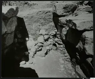 Excavation at Amathus with a cluster of pottery vessels lying on the floor between large stone blocks
