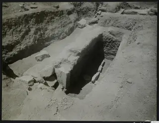 Tomb 14 at Amathus after excavation, showing a cut with a stone wall and loose stones on the excavated ground.