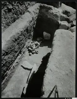 Excavation at Amathus: a cut trench with a cluster of pottery vessels and large stone blocks on its floor