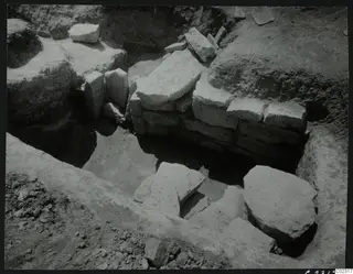 Excavation at Amathus showing a stone wall and scattered stone blocks in an excavated trench