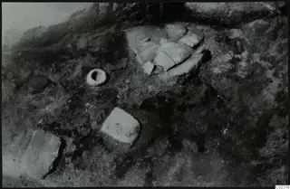 Excavation at Kythrea showing flat stone slabs and a small stone object lying in the soil