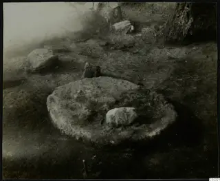 Excavated stone construction at Kythrea: a rounded, stone-edged feature in soil with scattered stones around it.