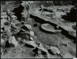 Excavation at Kythrea showing a stone construction, with a rounded stone base and scattered stones in a trench.