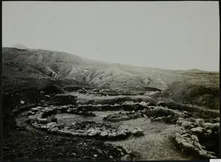 Excavation at Kythrea with low stone walls in a shallow trench, with bare hills rising behind