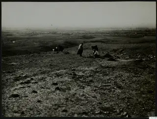 Rocky hillside at Kythrea with several people on the ground and a distant plain with trees