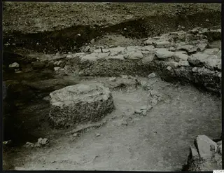 Excavation at Kythrea showing a stone wall and a round stone base in an excavated area