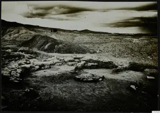 Excavated stone wall foundations at Kythrea, with a spoil heap and hills behind