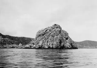 Petra tou Limniti, a large rocky outcrop rising from the sea, seen from the water.