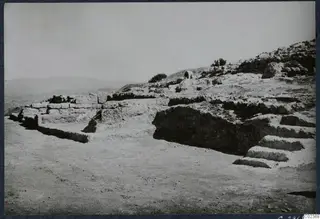 Ruined stone walls and a flight of steps on a rocky slope at Vouni, with hills in the distance