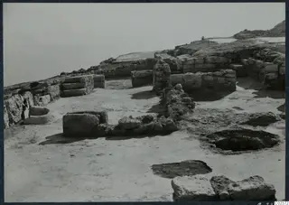 Excavated ruins of walls and stone foundations at the palace at Vouni, with a stone-lined basin on the left.