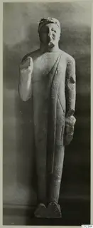 Standing limestone statue from Kition with broken arms, shown on a rectangular base.