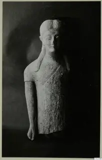 Limestone statue of a standing figure with a plait over one shoulder, shown against a dark background
