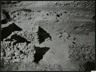 Temenos topography at Ayia Irini during excavation, with exposed stone walls, rubble and bushes